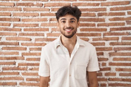 Téléchargez les photos : Arab man with beard standing over bricks wall background with a happy and cool smile on face. lucky person. - en image libre de droit