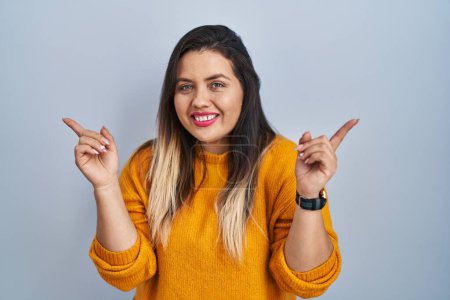 Téléchargez les photos : Jeune femme hispanique debout sur fond isolé souriant confiant pointant avec les doigts vers différentes directions. espace de copie pour la publicité - en image libre de droit