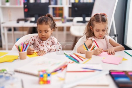 Foto de Two kids preschool students sitting on table drawing on paper at classroom - Imagen libre de derechos