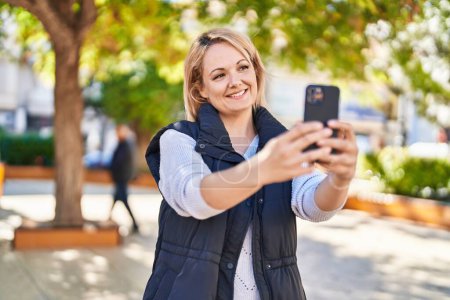 Téléchargez les photos : Jeune femme blonde souriante confiante faire selfie par le smartphone au parc - en image libre de droit