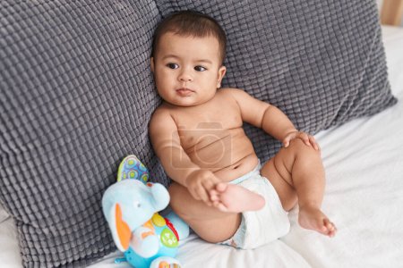 Téléchargez les photos : Adorable hispanic baby lying on bed at bedroom - en image libre de droit