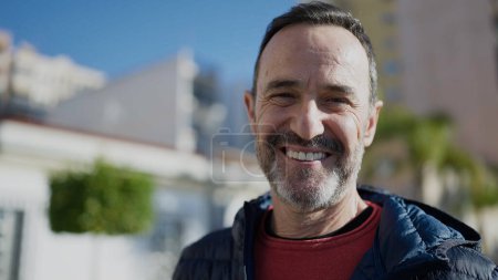 Téléchargez les photos : Homme d'âge moyen souriant confiant debout dans la rue - en image libre de droit
