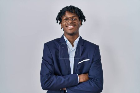 Téléchargez les photos : Jeune homme africain avec dreadlocks veste d'affaires sur fond blanc heureux visage souriant avec les bras croisés regardant la caméra. personne positive. - en image libre de droit