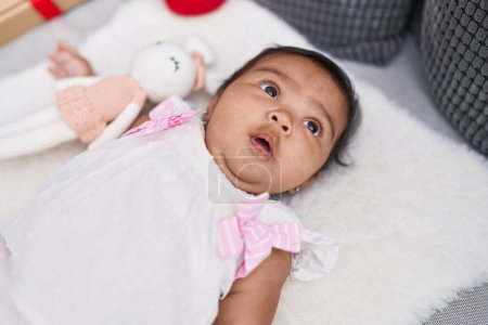 Téléchargez les photos : Bébé afro-américain couché sur le lit avec une expression détendue à la maison - en image libre de droit
