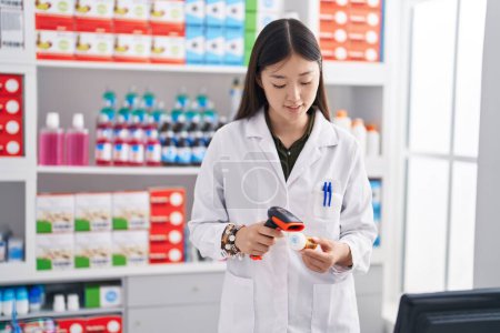 Foto de Chinese woman pharmacist scanning pills bottle at pharmacy - Imagen libre de derechos