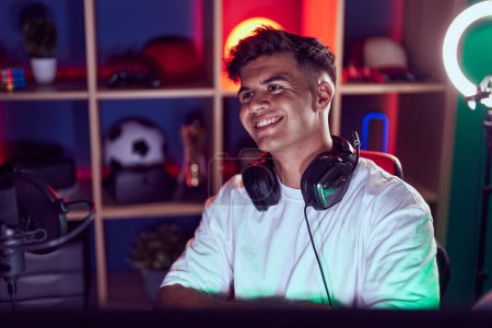 Photo for Young hispanic man streamer smiling confident sitting on table at gaming room - Royalty Free Image