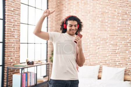 Foto de Joven latino bailando y escuchando música de pie en el dormitorio - Imagen libre de derechos