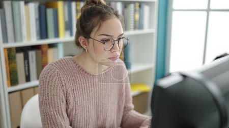 Téléchargez les photos : Young beautiful hispanic woman student using computer studying at library university - en image libre de droit