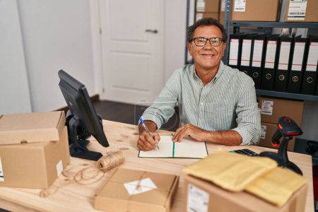 Téléchargez les photos : Middle age man ecommerce business worker writing on book at office - en image libre de droit