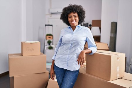Photo for African american woman smiling confident leaning on package at new home - Royalty Free Image