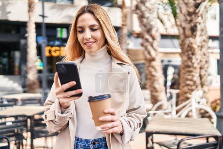 Téléchargez les photos : Jeune femme blonde utilisant un smartphone buvant du café sur la terrasse du café - en image libre de droit