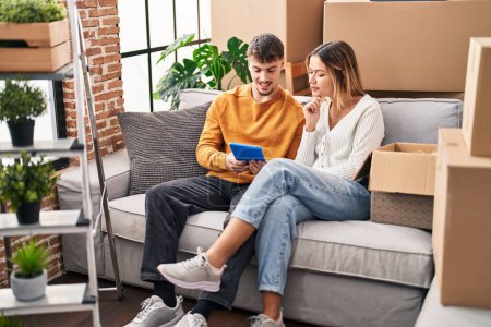 Photo for Young man and woman couple using touchpad sitting on sofa at new home - Royalty Free Image