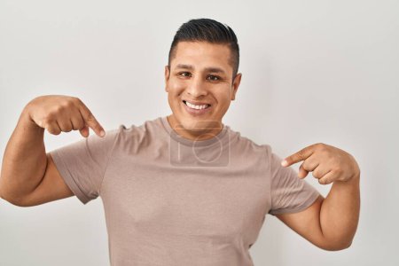 Photo for Hispanic young man standing over white background looking confident with smile on face, pointing oneself with fingers proud and happy. - Royalty Free Image