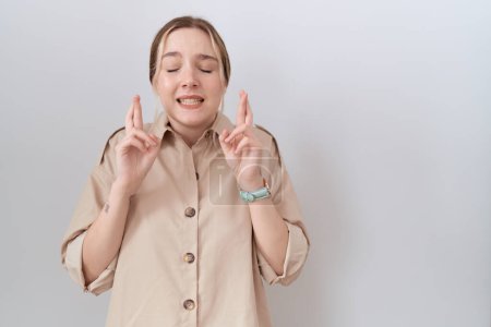 Téléchargez les photos : Young caucasian woman wearing casual shirt gesturing finger crossed smiling with hope and eyes closed. luck and superstitious concept. - en image libre de droit