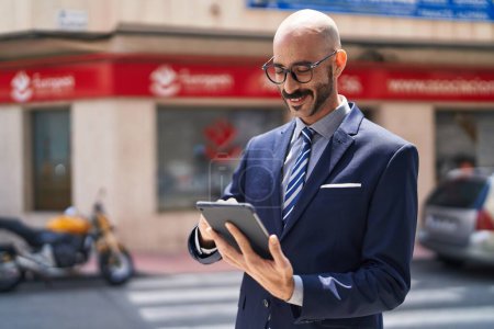 Photo for Young hispanic man executive smiling confident using touchpad at street - Royalty Free Image