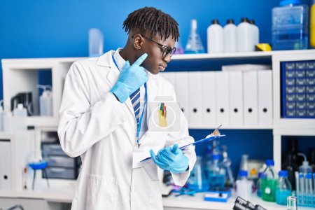 Téléchargez les photos : African american man scientist reading report with doubt expression at laboratory - en image libre de droit