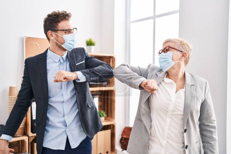 Photo for Mother and son business workers wearing medical mask make elbow greeting at office - Royalty Free Image