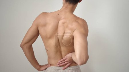 Foto de Joven hispano sufriendo de dolor de espalda sobre fondo blanco aislado - Imagen libre de derechos