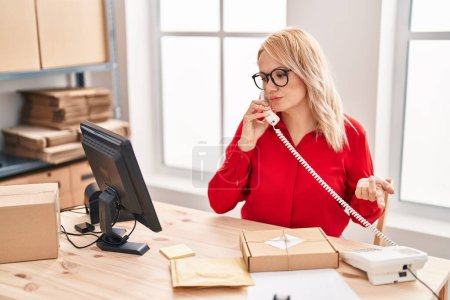 Photo for Young blonde woman ecommerce business worker talking on telephone at office - Royalty Free Image