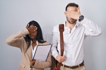 Téléchargez les photos : Couple d'affaires interraciaux portant des lunettes couvrant les yeux avec la main, l'air grave et triste. concept de non-visibilité, de dissimulation et de rejet - en image libre de droit