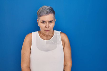 Photo for Middle age caucasian woman standing over blue background skeptic and nervous, frowning upset because of problem. negative person. - Royalty Free Image