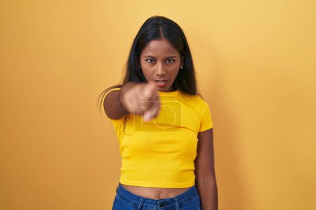 Photo for Young indian woman standing over yellow background pointing displeased and frustrated to the camera, angry and furious with you - Royalty Free Image