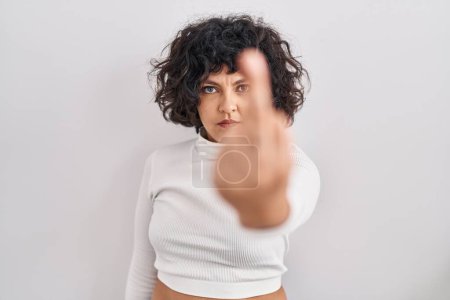 Foto de Hispanic woman with curly hair standing over isolated background showing middle finger, impolite and rude fuck off expression - Imagen libre de derechos