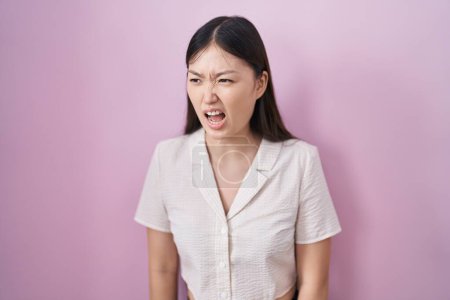 Téléchargez les photos : Jeune femme chinoise debout sur fond rose en colère et fou hurlant frustré et furieux, criant de colère. rage et concept agressif. - en image libre de droit
