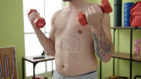 Foto de Young caucasian man training using weights at sport center - Imagen libre de derechos