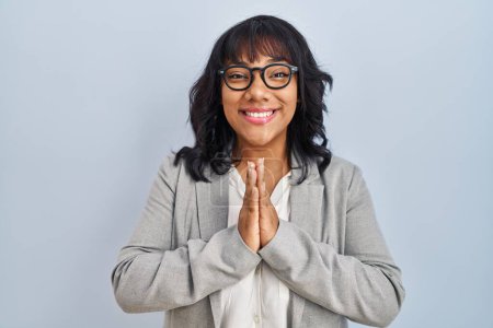Photo for Hispanic woman standing over isolated background praying with hands together asking for forgiveness smiling confident. - Royalty Free Image