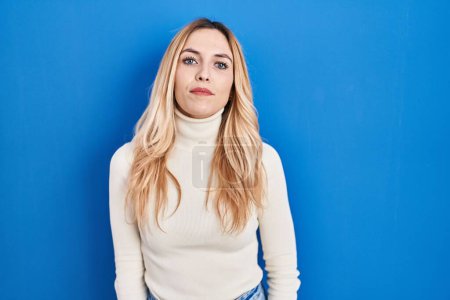 Photo for Young caucasian woman standing over blue background relaxed with serious expression on face. simple and natural looking at the camera. - Royalty Free Image
