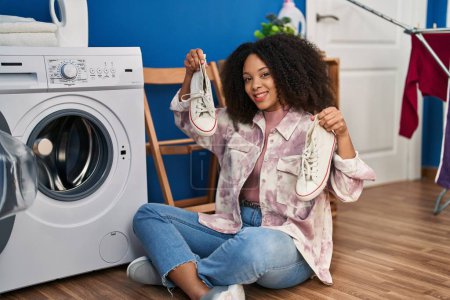 Photo for Young african american woman smiling confident washing sneakers at laundry - Royalty Free Image