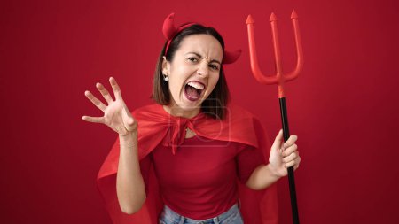 Téléchargez les photos : Young beautiful hispanic woman wearing devil costume doing scare gesture over isolated red background - en image libre de droit