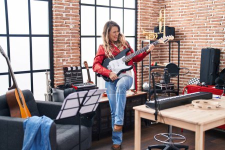 Téléchargez les photos : Young woman musician playing electrical guitar at music studio - en image libre de droit