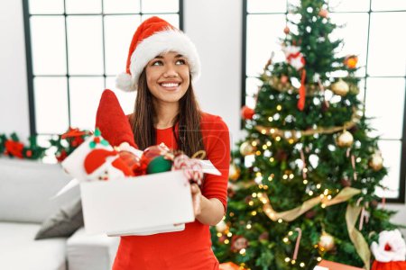 Téléchargez les photos : Jeune femme latine tenant boîte de décoration d'arbre de Noël à la maison - en image libre de droit