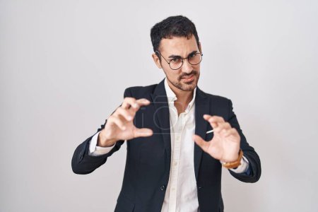 Téléchargez les photos : Beau business hispanique homme debout sur fond blanc souriant drôle faisant griffe geste comme chat, expression agressive et sexy - en image libre de droit