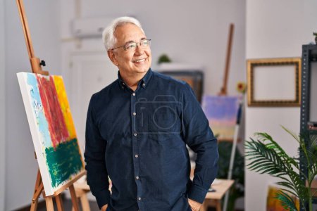 Foto de Hombre mayor sonriendo confiado de pie en el estudio de arte - Imagen libre de derechos
