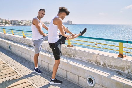 Photo for Two hispanic men couple smiling confident stretching at seaside - Royalty Free Image