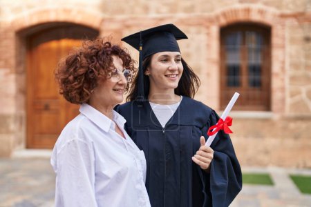 Photo for Two women mother and daughter holding graduate diploma at campus university - Royalty Free Image