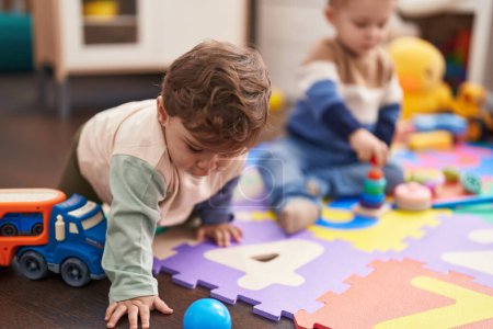 Photo for Two kids sitting on floor playing with toys at kindergarten - Royalty Free Image