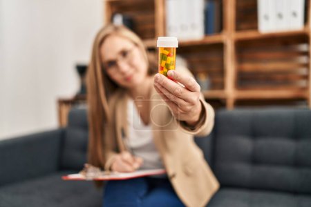 Foto de Young blonde woman psychologist prescribe pills at psychology clinic - Imagen libre de derechos