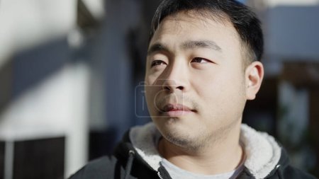 Téléchargez les photos : Jeune homme chinois regardant vers le côté avec une expression sérieuse à la rue - en image libre de droit
