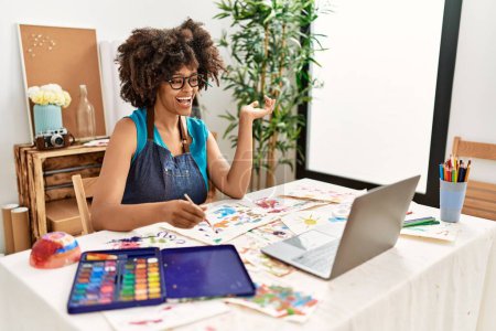 Téléchargez les photos : Jeune femme afro-américaine souriante confiante ayant cours de dessin en ligne au studio d'art - en image libre de droit