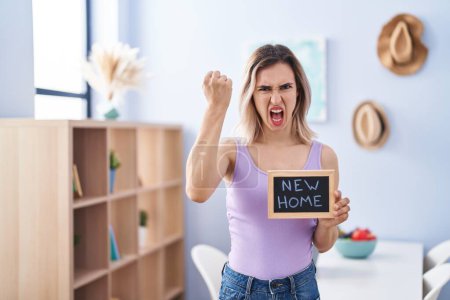 Téléchargez les photos : Young beautiful woman moving to a new home annoyed and frustrated shouting with anger, yelling crazy with anger and hand raised - en image libre de droit