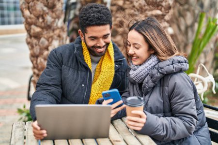 Téléchargez les photos : Homme et femme couple en utilisant ordinateur portable et smartphone boire du café à la terrasse du café - en image libre de droit