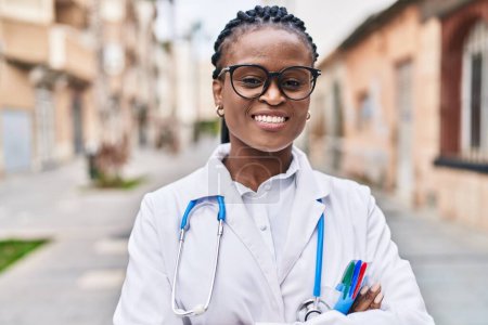 Téléchargez les photos : African american woman doctor smiling confident standing with arms crossed gesture at street - en image libre de droit