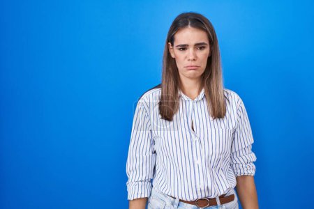 Photo for Hispanic young woman standing over blue background depressed and worry for distress, crying angry and afraid. sad expression. - Royalty Free Image