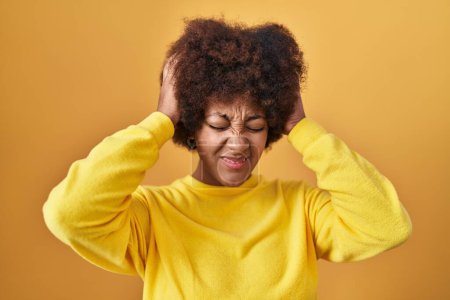 Téléchargez les photos : Young african american woman standing over yellow background suffering from headache desperate and stressed because pain and migraine. hands on head. - en image libre de droit