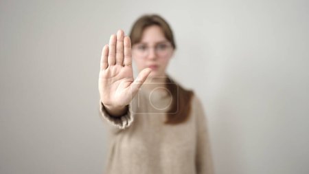 Foto de Young blonde woman doing stop gesture with hand over isolated white background - Imagen libre de derechos