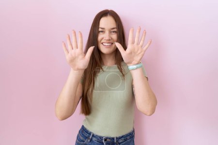 Photo for Beautiful brunette woman standing over pink background showing and pointing up with fingers number ten while smiling confident and happy. - Royalty Free Image